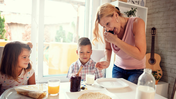 Mutter am Telefon während des Frühstücks