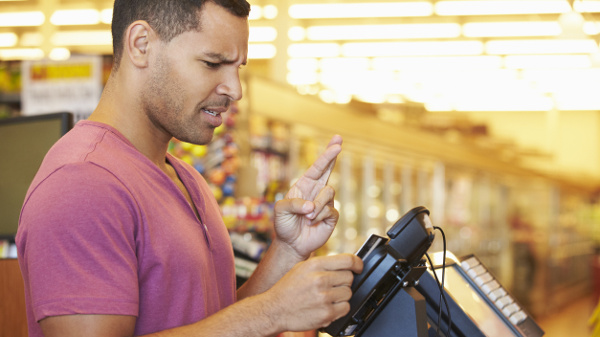 Mann steht im Supermarkt an der Kasse und hofft, dass seine EC-Karte funktioniert