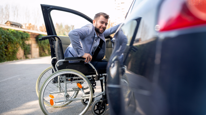 Rollstuhlfahrer beim Einsteigen ins Auto